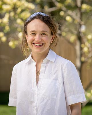 A photo of a brown haired woman wearing a white shirt