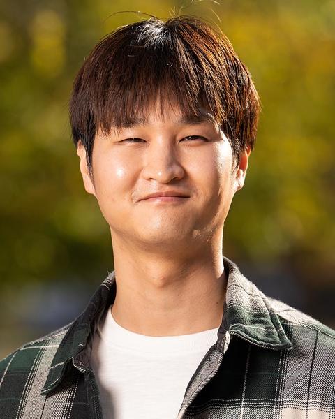 A photo of a dark haired man standing outside