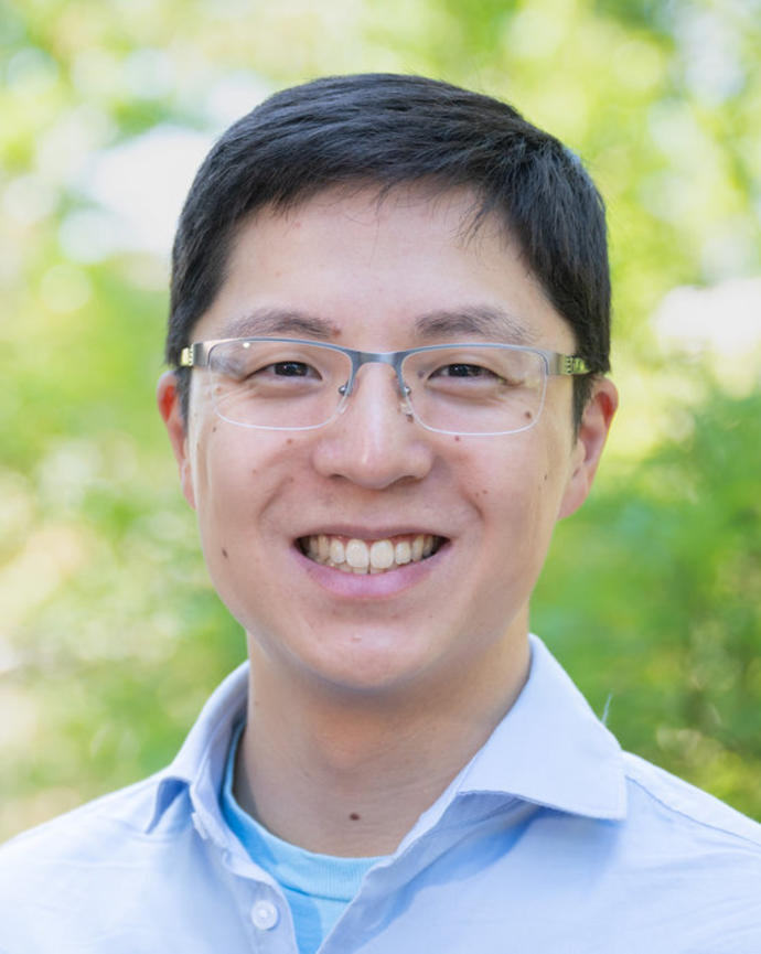 A photo of a dark haired man wearing a light blue collared shirt